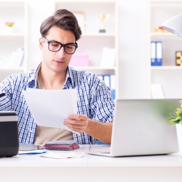 nextiva vfax overview online fax service man with glasses reading papers faxes sending faxes  laptop on desk